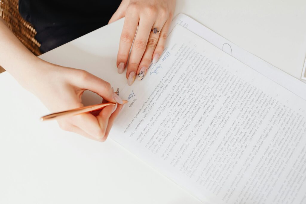 Close-up of woman's hands signing a legal document with elegant nail art using a pen.